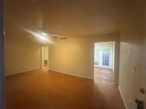 a view of an empty room with wooden floor and a window