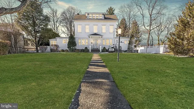 a front view of a house with a garden and trees