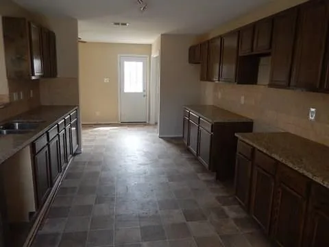 a kitchen with granite countertop a stove top oven microwave and cabinets