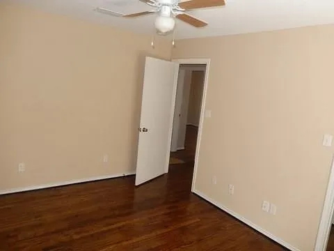 an empty room with wooden floor and fan