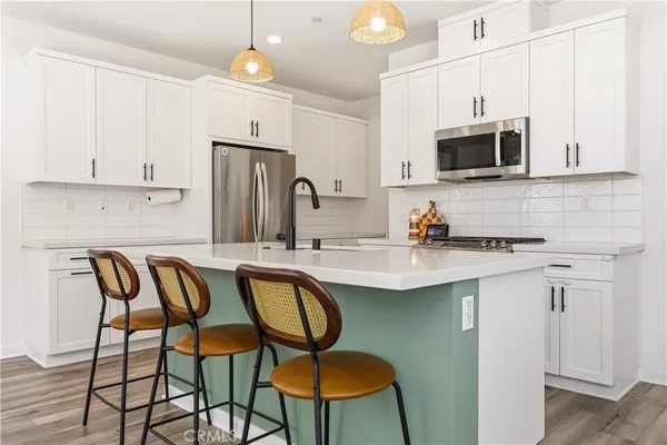 a kitchen with stainless steel appliances granite countertop a white table chairs microwave and sink