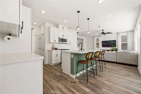 a kitchen with stainless steel appliances kitchen island granite countertop a stove a sink a refrigerator and a dining table with wooden floor