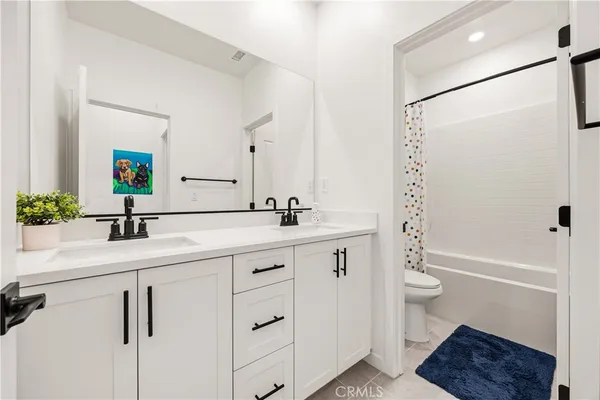 a bathroom with a double vanity sink a toilet and shower