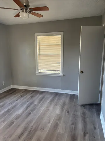 a view of an empty room with a window and chandelier fan
