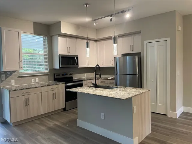 a kitchen with granite countertop a refrigerator stove top oven and sink