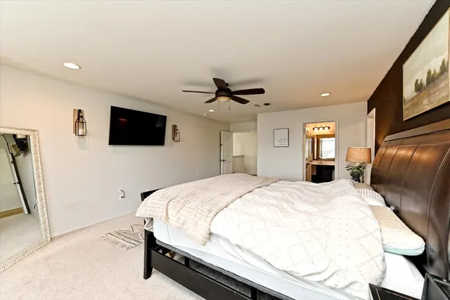a spacious bedroom with a bed and a flat screen tv
