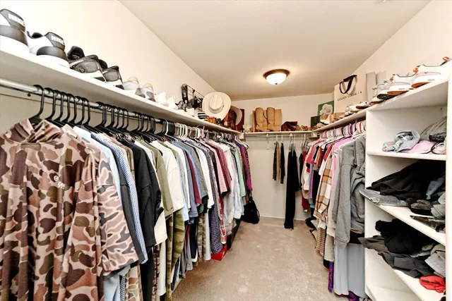 a view of walk in closet with clothes and shoes