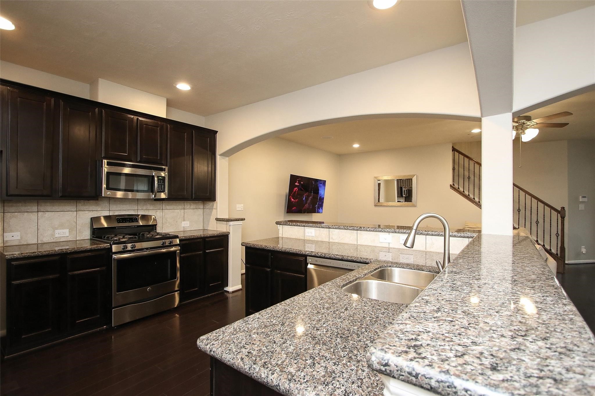 8517 Sunset Loch Drive Spring, TX 77379 - Photo 11 of 22 a kitchen with stainless steel appliances granite countertop a sink stove microwave and refrigerator