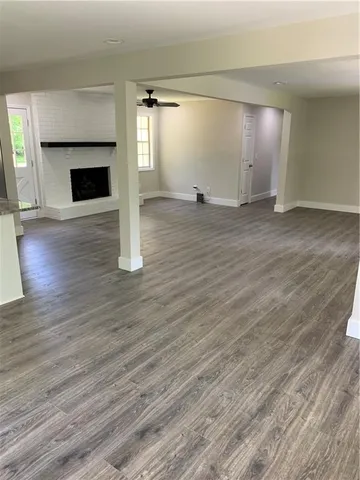 an empty room with wooden floor fireplace and windows