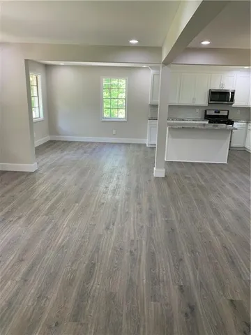 an empty room with wooden floor and a kitchen