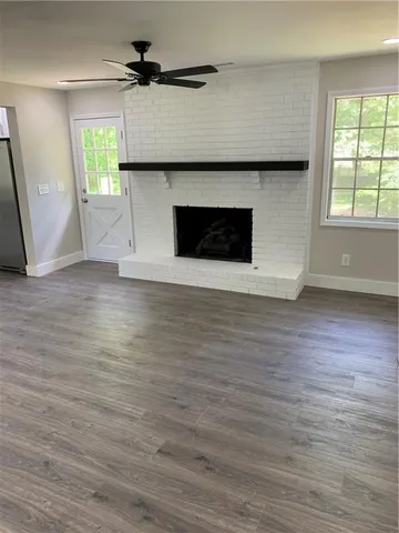 an empty room with wooden floor a fireplace and windows