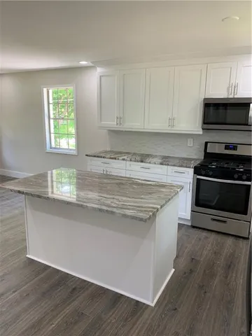 a kitchen with granite countertop a stove a sink and a microwave