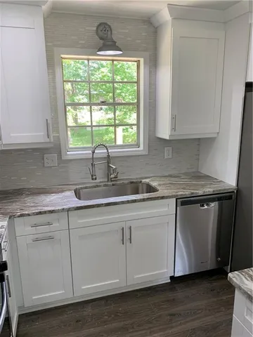a kitchen with stainless steel appliances granite countertop white cabinets a sink and a large window