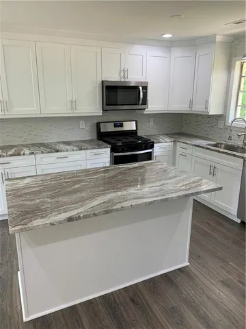 a kitchen with kitchen island granite countertop a stove a microwave and wooden cabinets