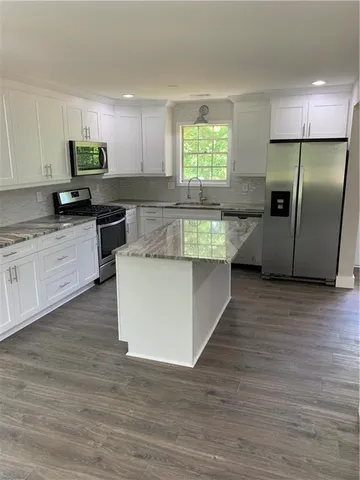a large kitchen with kitchen island a large counter top space a sink stainless steel appliances and cabinets