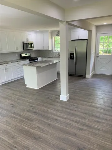 a kitchen with granite countertop a refrigerator and a stove top oven
