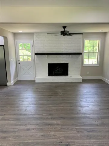an empty room with wooden floor a fireplace and windows