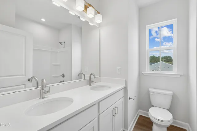 a bathroom with a toilet a sink a mirror a vanity and window