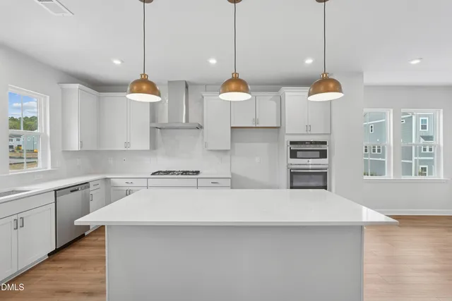 a kitchen with stainless steel appliances a stove a sink a center island a stove and a window