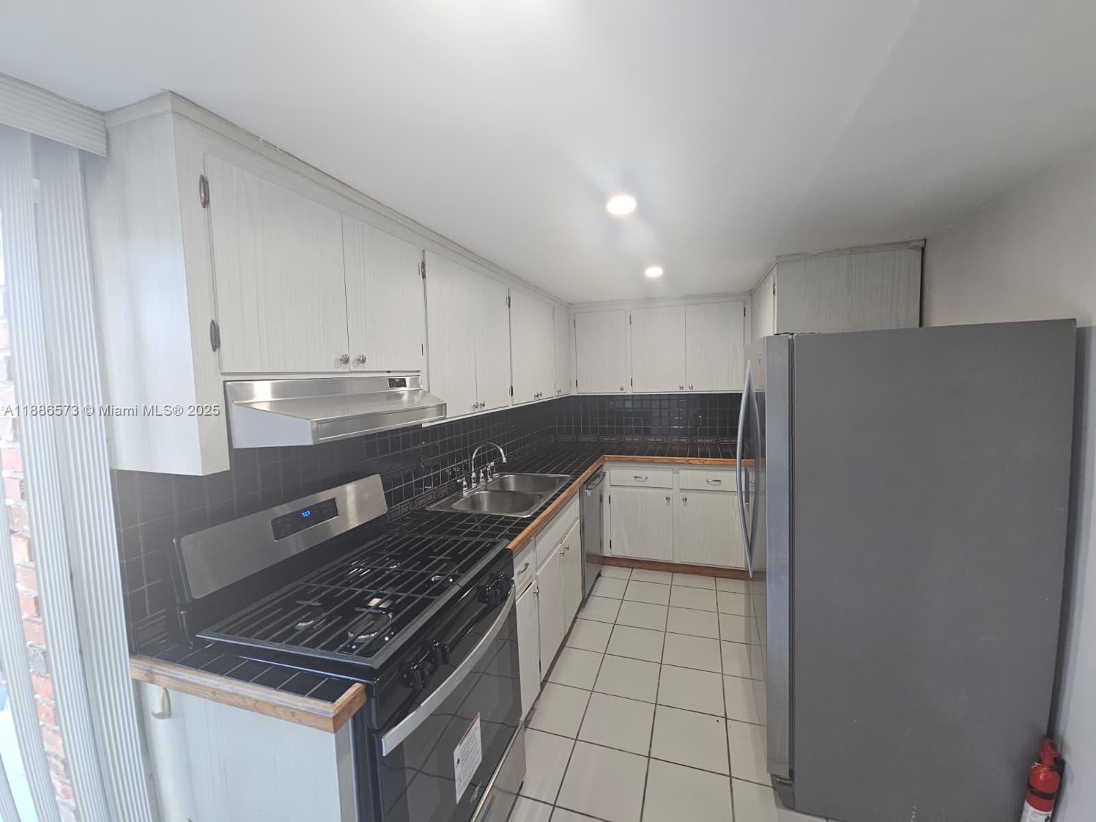 6782 Brookline Drive, Unit 6782 Hialeah, FL 33015 - Photo 13 of 27 a kitchen with a sink a stove and cabinets