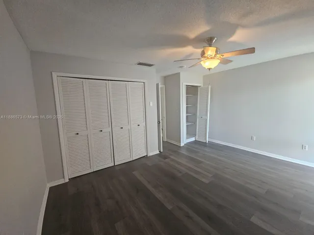 a view of a bedroom with wooden floor and a ceiling fan
