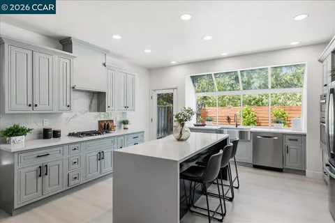 a kitchen with white cabinets and wooden floors