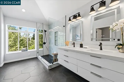 a spacious bathroom with a double vanity sink a mirror and a shower