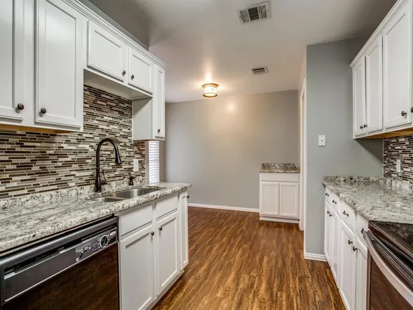 a kitchen with granite countertop a sink cabinets and stainless steel appliances
