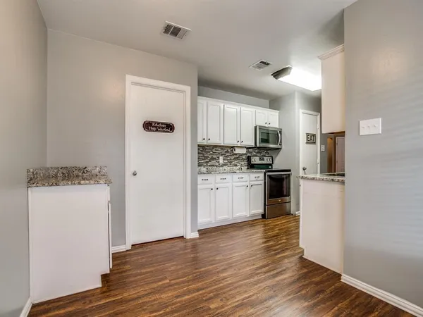 a kitchen with a refrigerator a stove top oven and white cabinets