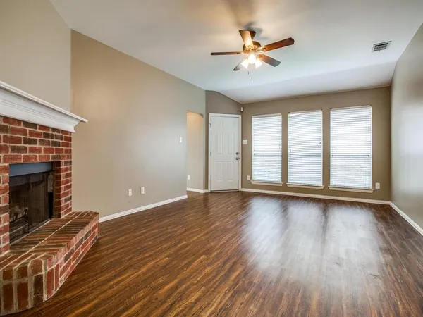 an empty room with wooden floor ceiling fan and windows