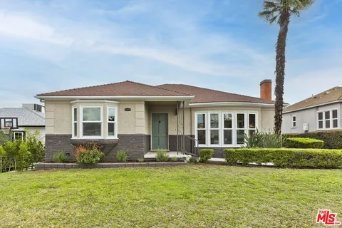 a front view of a house with a yard and potted plants