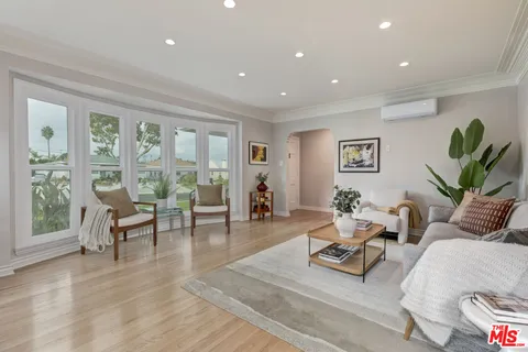 a living room with furniture hard wood floor and a floor to ceiling window