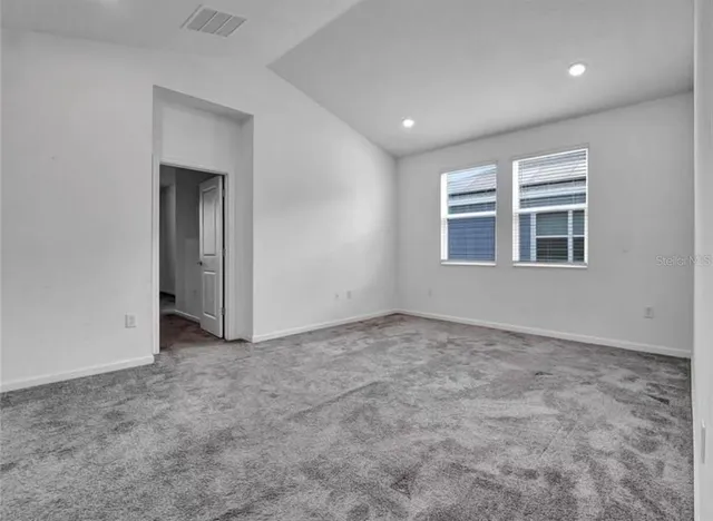 an empty room with a ceiling fan and windows
