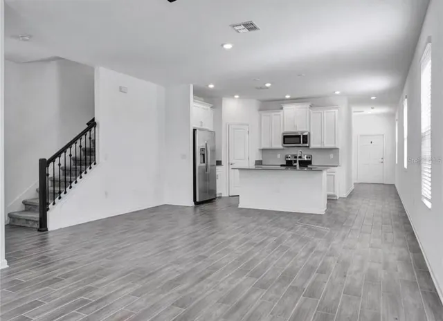 a view of an empty room with wooden floor and a sink