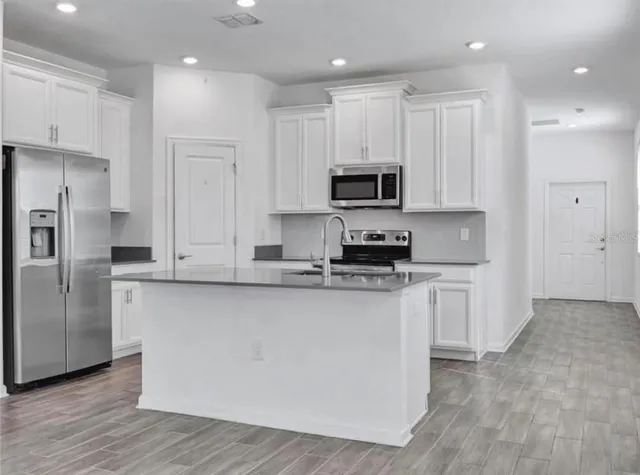 a kitchen with stainless steel appliances granite countertop a stove a sink and a refrigerator