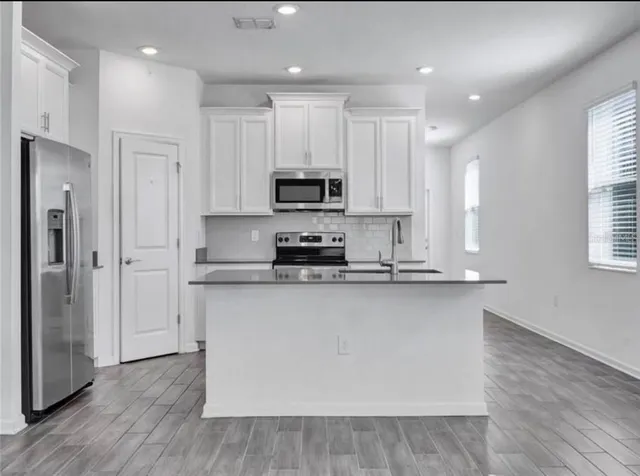 a kitchen with stainless steel appliances granite countertop a stove a sink and a refrigerator