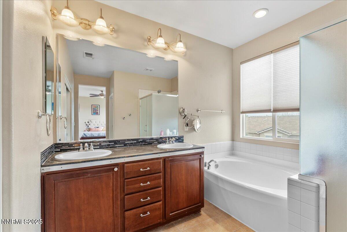 10755 Copper Lake Drive Reno, NV 89521 - Photo 19 of 40 a bathroom with a tub a double vanity sink and a mirror