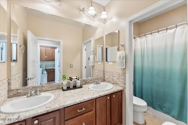 a bathroom with a granite countertop sink a toilet a mirror a vanity and shower