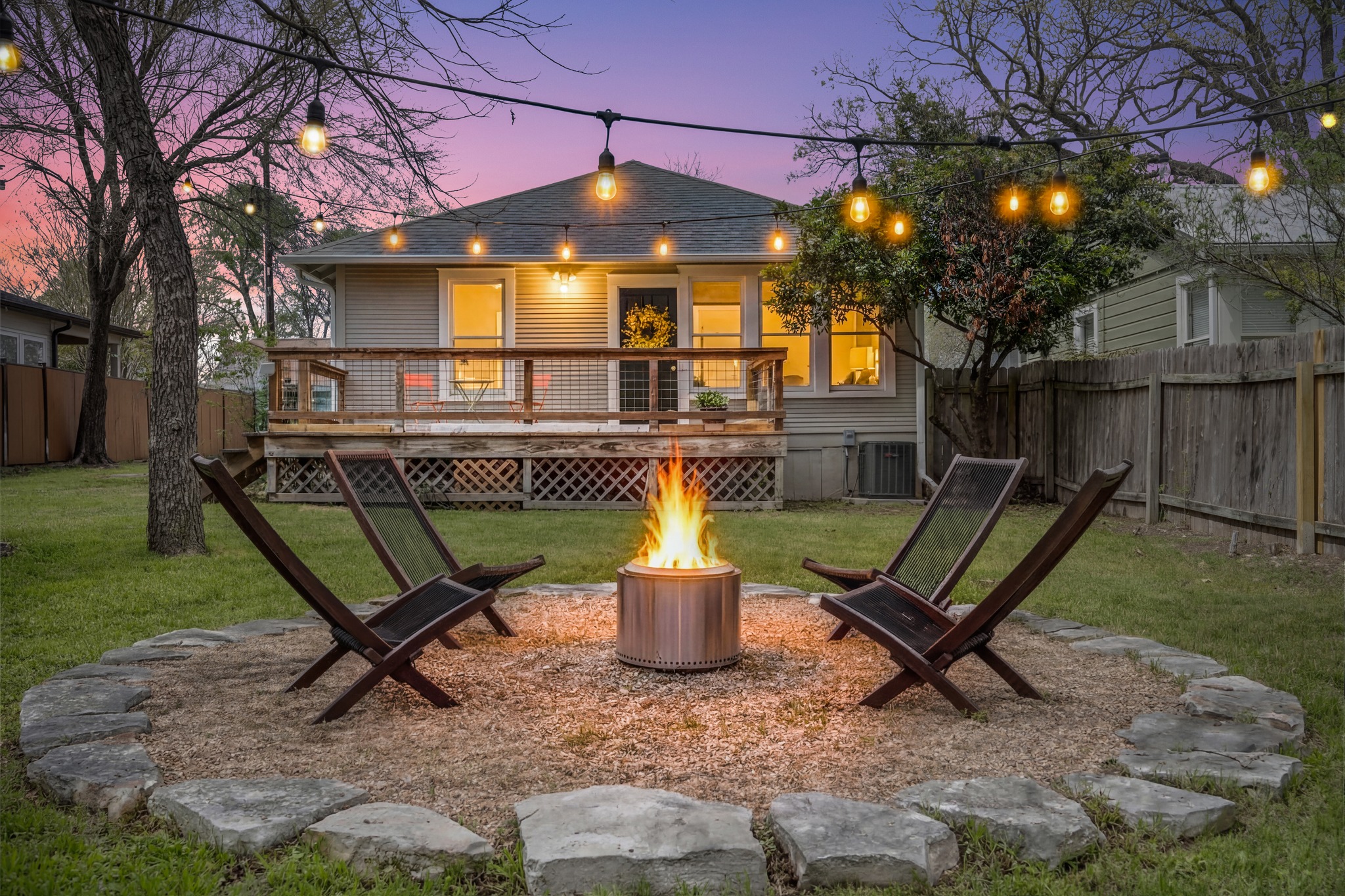 3909 Becker Avenue Austin, TX 78751 - Photo 5 of 38 Back of house at dusk featuring an outdoor fire pit, a fenced backyard, a deck, and roof with shingles