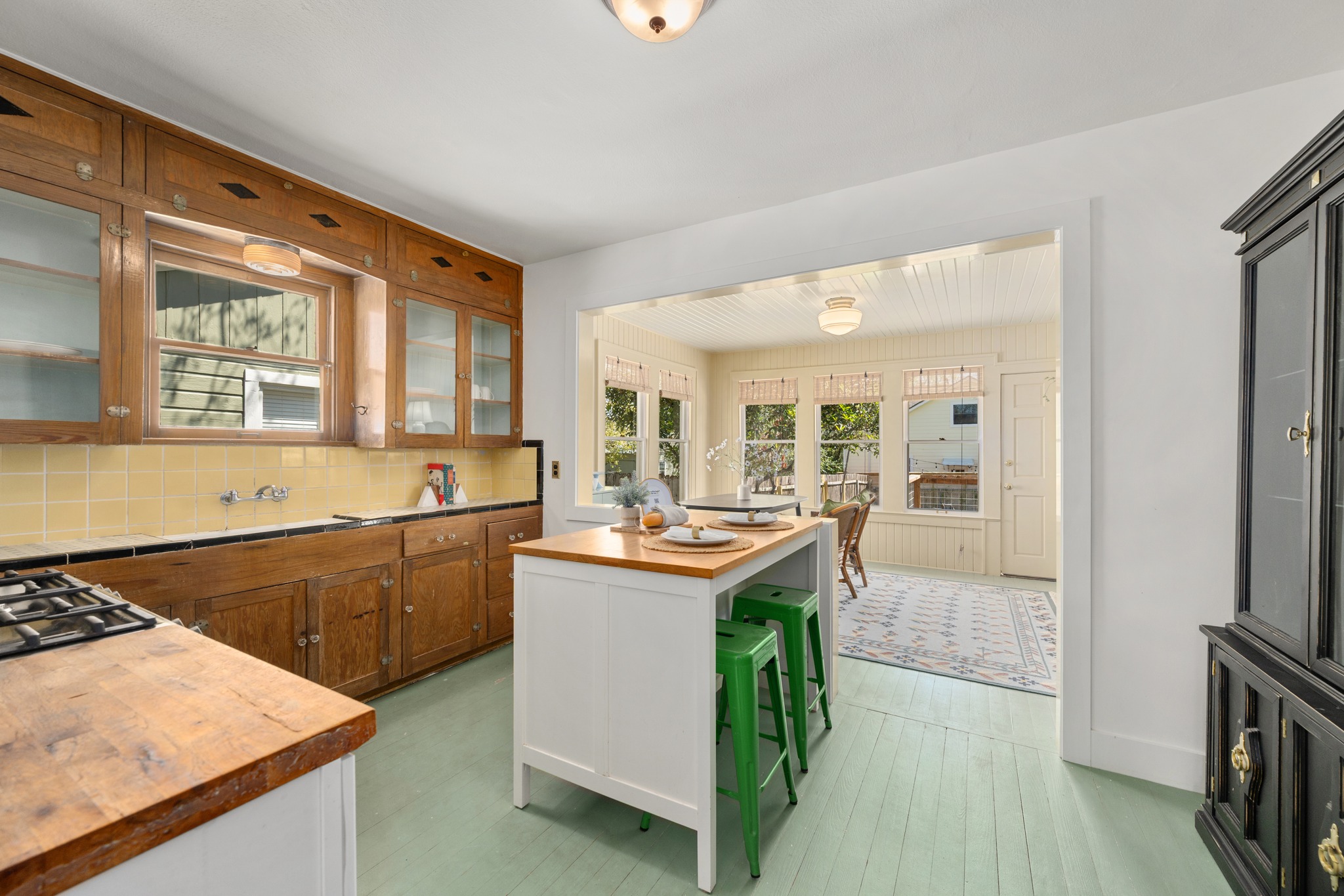 3909 Becker Avenue Austin, TX 78751 - Photo 10 of 38 Kitchen featuring butcher block countertops, glass insert cabinets, tasteful backsplash, two tone color scheme, and a center island