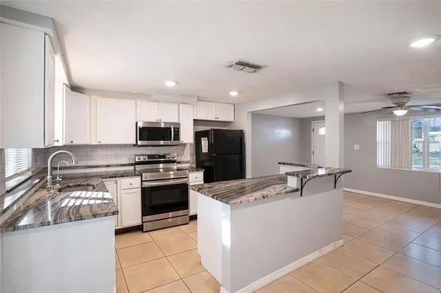 a kitchen with stainless steel appliances kitchen island granite countertop a stove top oven a sink a counter top space and cabinets