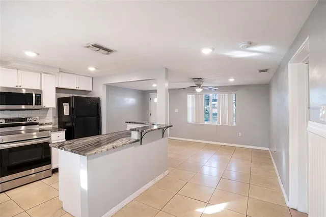 a large kitchen with kitchen island granite countertop a stove top oven a sink a counter space and cabinets