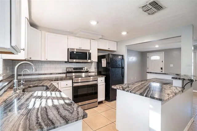 a kitchen with granite countertop a sink and stainless steel appliances