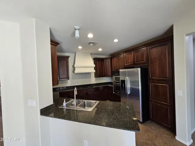a kitchen with kitchen island granite countertop a refrigerator and a sink