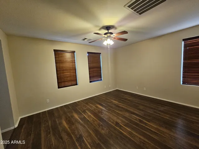 a view of an empty room with window and chandelier fan