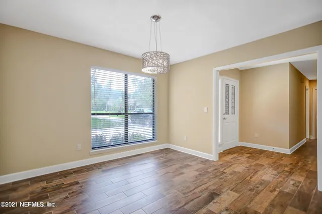 a view of a room with window wooden floor and front door