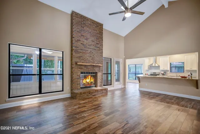 an empty room with wooden floor a fireplace and windows