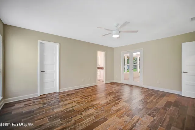 a view of an empty room with window and wooden floor