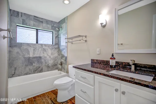 a bathroom with a granite countertop sink a toilet and bathtub