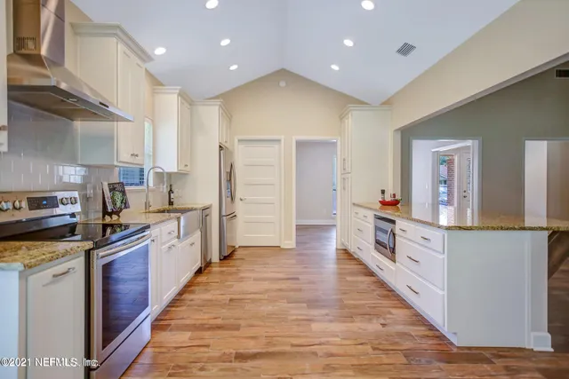 a large kitchen with stainless steel appliances double vanity and a refrigerator